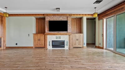 A beautifully designed living room with custom oak built ins, brick fireplace surround, and durable wood look flooring. Ideal for relaxing or hosting in this thoughtfully designed Phoenix residence.