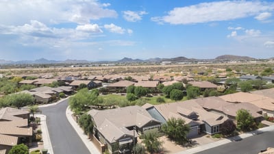 A panoramic aerial shot highlights the peaceful Phoenix neighborhood with mountain vistas, wide streets, and proximity to open desert terrain.