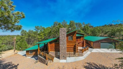 Elevated view showcasing the home s placement among rolling hills and pine trees, highlighting the expansive lot and peaceful Prescott environment.