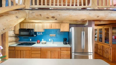 Detailed kitchen view highlighting natural wood cabinetry, gas cooking, and stainless steel appliances that blend rustic charm with modern convenience.