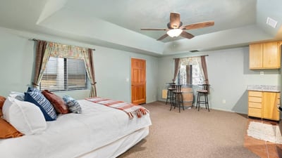 Private lower-level guest suite offering bedroom space, ceiling fan, and nearby kitchenette for extended stays or flexible living.