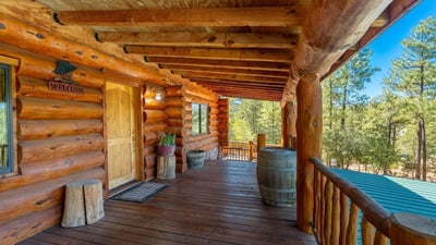 Covered front deck with log details and forest surroundings, setting the tone for this distinctive Prescott property.