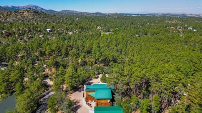 Broad aerial view showcasing dense pine forest and rolling terrain. The property s location offers scenic beauty, quiet surroundings, and a connection to nature unique to Prescott living.