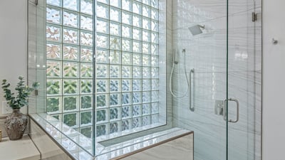 Spacious glass shower with rainfall fixture, handheld sprayer, and sleek tilework offers modern luxury.