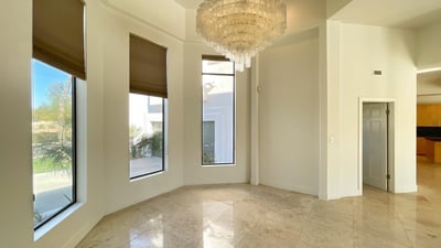 Elegant dining room featuring a stunning chandelier, soaring ceilings, and tall windows that fill the space with warmth and sophistication.