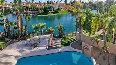 Resort-style setting featuring sparkling pool, lush palms, and lakefront patio. Scottsdale outdoor living at its finest.