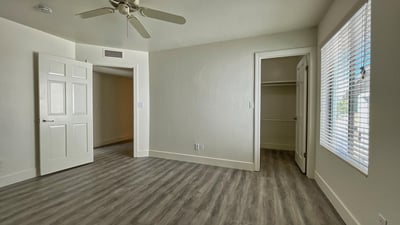Relaxing bedroom with soft neutral tones, ceiling fan, and ample closet storage, offering comfort and tranquility.