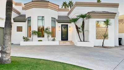 Striking entryway with tall windows, modern iron door, and smooth stucco finish for a sophisticated curb presence.