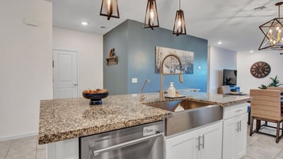 Contemporary pendant lights accent the large island and farmhouse sink, enhancing the kitchen s modern feel and energy-efficient layout in Litchfield Park.