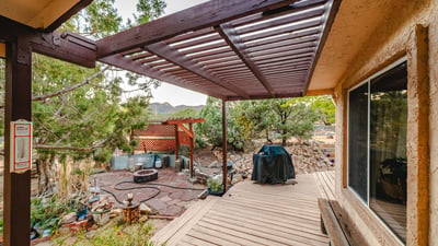Featuring a shaded pergola, natural stonework, and mountain scenery, this outdoor patio is perfect for BBQs, lounging, and taking in the desert surroundings.
