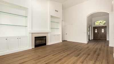 Elegant Scottsdale living space featuring custom built-in shelving surrounding a cozy fireplace. The clean white cabinetry and modern flooring add both style and storage to this beautifully updated interior.