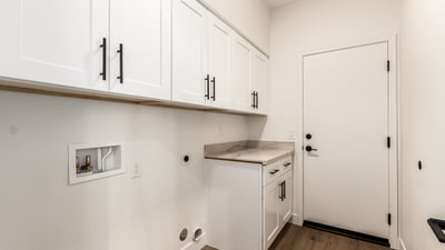 Well-designed Scottsdale laundry room featuring overhead cabinets, counter space, and washer/dryer hookups. The organized layout provides convenient storage and everyday functionality for household tasks.