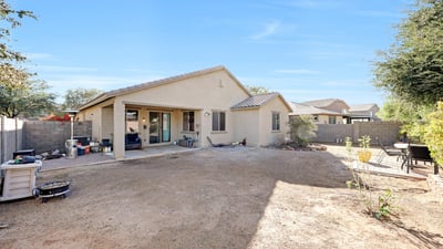 Rear view of the home showing a covered patio and open yard, offering versatile outdoor living and entertaining possibilities.