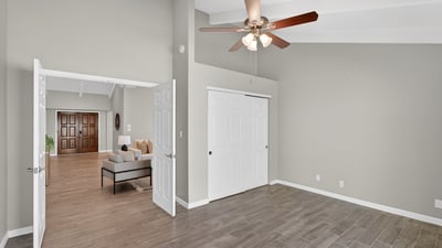 Guest bedroom with vaulted ceiling, neutral tones, and tile flooring, offering comfort and versatility for multiple living needs.