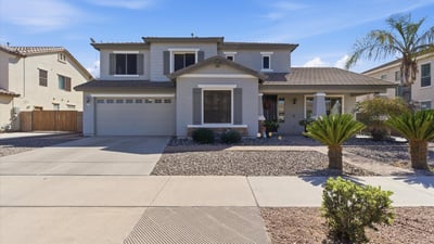 Attractive exterior of this Queen Creek property featuring a covered entry, desert landscaping, and attached garage in the popular Cortina community.