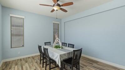 Bright dining room with wood-style flooring, ceiling fan, and neutral walls creating a welcoming setting for gatherings and meals.