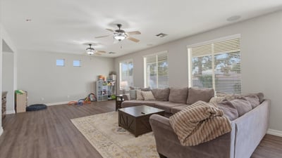 Large family room with multiple windows and modern flooring, offering plenty of space for relaxing, entertaining, or movie nights.