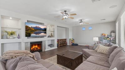 Comfortable great room with fireplace centerpiece, built-in shelving niches, and wood-style flooring, creating a welcoming space for relaxing or entertaining guests.