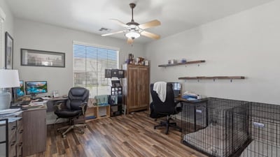 Spacious office area with wood-style flooring and large window, ideal for remote work, study, or a hobby room within this Queen Creek home.