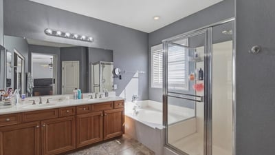 Primary bathroom with dual sinks, wood cabinetry, and bright lighting, providing a functional and stylish space for daily routines.