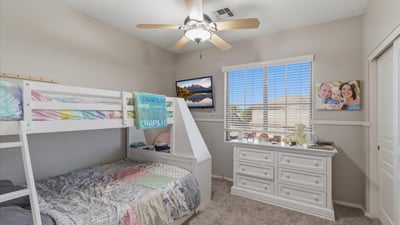 Cozy secondary bedroom with bunk bed arrangement, neutral paint, and large window allowing natural light into the room.