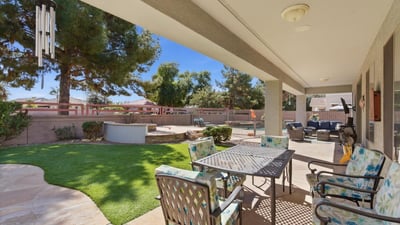 Shaded patio overlooking the landscaped yard and pool area, providing a comfortable outdoor living space for dining or relaxing.