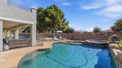 Sparkling backyard pool with spa, stone decking, and lounge space surrounded by mature trees for added privacy and shade.