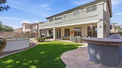 Private backyard retreat with artificial turf lawn, shaded patio seating, and fenced pool and spa area providing a perfect outdoor living space in this Queen Creek home.