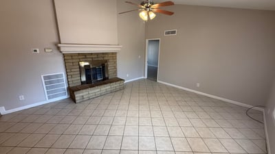 Comfortable living room featuring tile flooring, neutral colors, vaulted ceilings, and a stone fireplace centerpiece. This Glendale home provides a cozy environment for relaxing evenings.