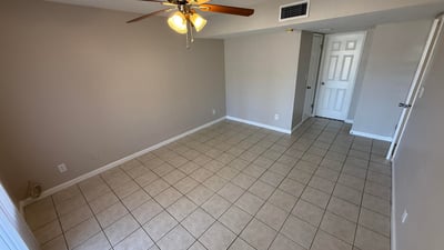 Light-filled bedroom with tile floors and large window providing exterior views. The space offers a bright environment ideal for relaxation.
