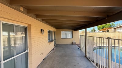 Covered patio space overlooking the fenced backyard pool area. The shaded outdoor living space is perfect for relaxing evenings or entertaining guests.