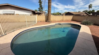Private Pebble Tec pool surrounded by desert landscaping and tall palm trees. The backyard offers a peaceful outdoor retreat ideal for enjoying Glendale s sunny climate.
