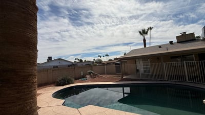 Inviting Pebble Tec pool surrounded by desert landscaping and privacy fencing. The outdoor space creates a refreshing retreat perfect for enjoying Glendale s warm weather.