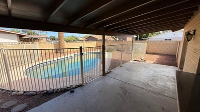 Covered backyard patio offering shade and direct views of the fenced pool area. This outdoor living space is perfect for entertaining guests or enjoying peaceful afternoons.