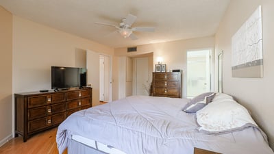 Spacious primary bedroom featuring neutral finishes, hardwood floors, and convenient access to the ensuite bath.