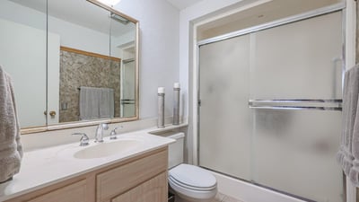 Primary bathroom with walk-in shower, large vanity, and bright lighting, designed for functionality and comfort in this Sun City property.