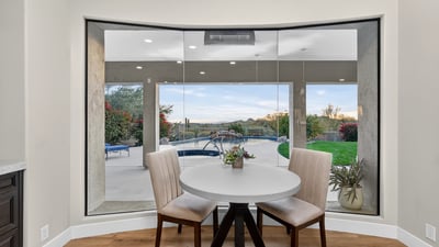 Bright dining nook with large windows framing views of the pool and patio, bringing natural light and Scottsdale outdoor beauty indoors.