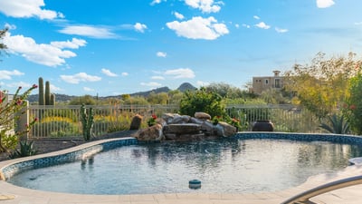 Scottsdale backyard with sparkling pool, water feature, and desert views, perfect for relaxing or entertaining outdoors.