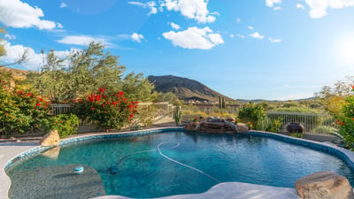 Scottsdale pool with rock waterfall feature, desert landscaping, and mountain views, offering a serene and private outdoor setting.