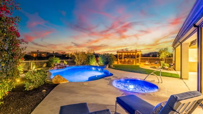 Scottsdale backyard with pool, spa, pergola, and outdoor kitchen, beautifully lit at sunset for relaxing evenings and entertaining.