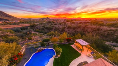 Scottsdale aerial capturing expansive desert scenery, nearby homes, and vibrant sunset skies.