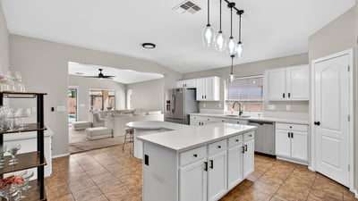 Spacious kitchen with large island, white cabinetry, and ample prep space. Open layout flows into living areas, making it ideal for gatherings in this Casa Grande property.