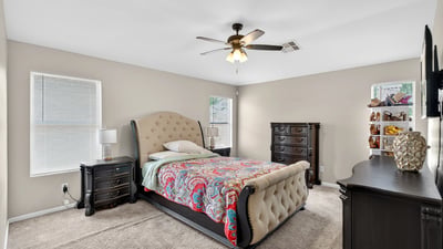 Generous primary bedroom with ceiling fan, soft carpet, and multiple windows. A relaxing retreat designed for comfort in this Casa Grande home.