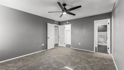 Comfortable primary bedroom with soft carpet, ceiling fan, and neutral palette. This Sun City home includes updated features and easy access to a renovated bathroom.