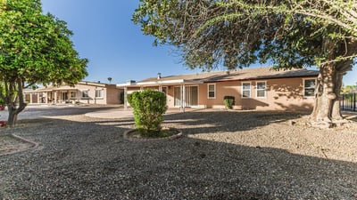 Backyard featuring mature trees offering shade and privacy. This Sun City home includes spacious outdoor areas perfect for relaxation.