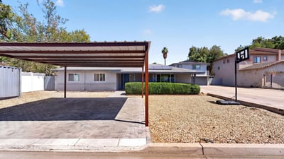 Well-maintained Phoenix property featuring a covered carport, paved parking, and desert landscaping perfect for low-maintenance multi-unit living.