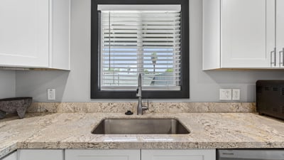 Window-lined sink area with granite counters and modern fixtures, creating a bright and functional kitchen workspace.