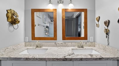 Stylish bathroom with dual sinks, granite counters, and updated lighting, designed for comfort and convenience.
