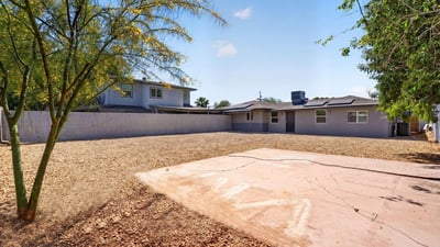 Private backyard with concrete pad and mature landscaping, offering versatile outdoor living potential in this Phoenix home.