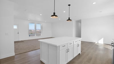 Stunning kitchen featuring an oversized center island, shaker cabinetry, modern lighting, and open sightlines to the living area. This impressive space is ideal for cooking, dining, and gathering with guests.